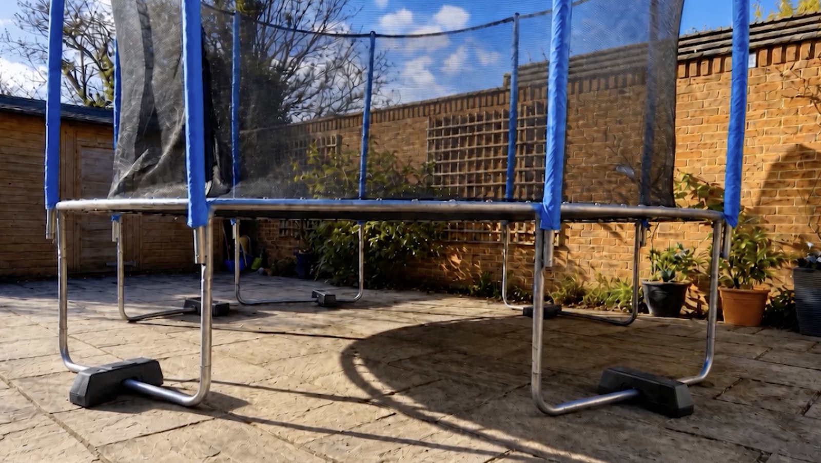 A full-size residential trampoline with Trampoline Weights installed on the ground tubes